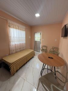 a bedroom with a bed and a table and chairs at pousada Bela Rosa in Santa Cruz Cabrália