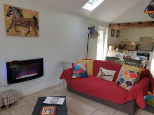 a living room with a red couch and a fireplace at Stable Cottage at Hanley Mill in Tenbury