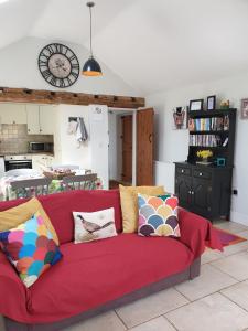 a red couch with pillows in a living room at Stable Cottage at Hanley Mill in Tenbury