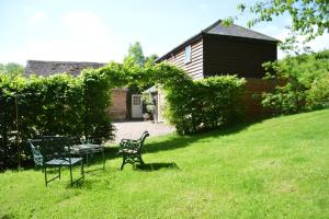 a yard with two chairs and a table in the grass at Stable Cottage at Hanley Mill in Tenbury
