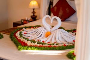 a cake with two swans forming a heart on a bed at Warung Mandi & Villa in Ubud +12 photos