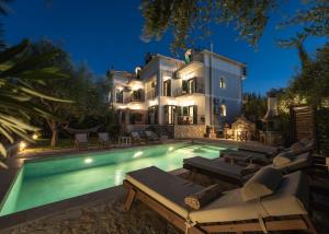 a villa with a swimming pool in front of a house at Joya Luxury Villas in Kypseli
