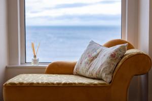 a chair with a pillow sitting in front of a window at Manse On The Beach in Kirkistown