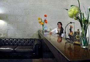 una mujer sentada en un escritorio en una habitación con flores en Hoteles Riviera Mansion, en Arequipa