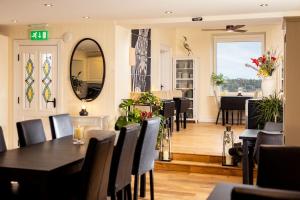 a dining room with a table and chairs and a mirror at Manse On The Beach in Kirkistown