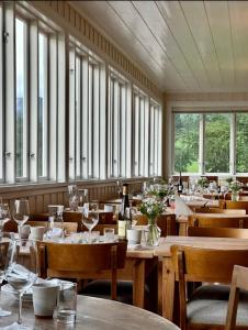 a dining room with tables and chairs and windows at Sommerhotellet in Vang I Valdres