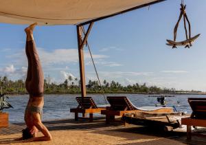 a man doing yoga on a dock with a plane at Yara Floating Villa in Guriú