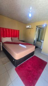 a large bed with a red headboard and a red rug at 6 Tiger guest house in Katlehong
