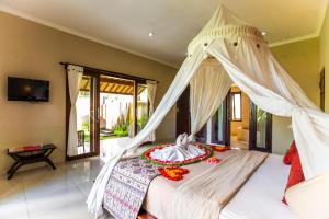 a bedroom with a white bed with a canopy at Warung Mandi & Villa in Ubud