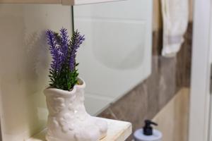 a white vase with purple flowers in it on a shelf at D&A Apartments in Novi Pazar +24 photos