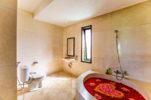 a bathroom with a bath tub with a red rug at Warung Mandi & Villa in Ubud
