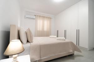 a white bedroom with a bed and a lamp at Greca Apartments in Sauk +73 photos