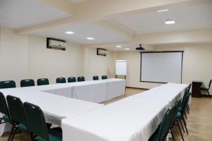 a conference room with white tables and chairs and a whiteboard at Hotel Premium Pirassununga in Pirassununga