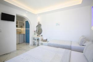ein weißes Zimmer mit einem Bett und einem Spiegel in der Unterkunft Augusta Studios & Apartments in Naoussa
