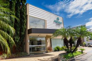 a building with a palm tree in front of it at Hotel Premium Pirassununga in Pirassununga