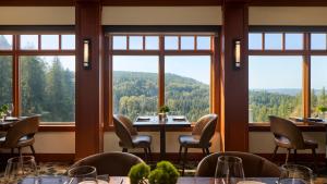 a restaurant with tables and chairs and large windows at Salish Lodge & Spa in Snoqualmie