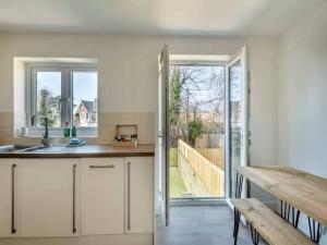 a kitchen with white cabinets and a sliding glass door at Beachside Bliss in Paignton +10 photos