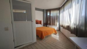 a bedroom with a bed with an orange blanket and a window at Hotel de la Cruz in Maguey Blanco