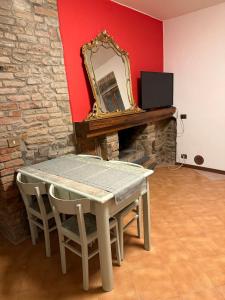 a table with chairs and a mirror on a wall at Residenza Il Castello Tre in CastellʼArquato