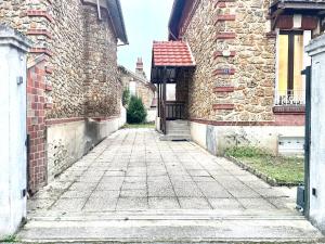 an alley between two brick buildings with a gate at Maison Villa Foch in Meaux