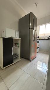 a kitchen with a stainless steel refrigerator and appliances at Kit net a poucos passos do mar in São Vicente +3 photos