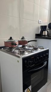 two pots on top of a stove in a kitchen at Kit net a poucos passos do mar in São Vicente
