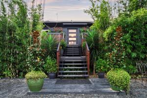 a house with a staircase in a garden with plants at Cypress BnB in Hervey Bay +5 photos