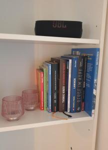 a book shelf with books and glasses on it at Frisch renoviertes BergSeeNest in Bad Bayersoien