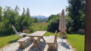 a wooden picnic table with an umbrella and a chair at Frisch renoviertes BergSeeNest in Bad Bayersoien