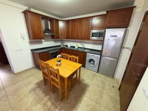 a kitchen with a wooden table with chairs and a refrigerator at Valthi in La Restinga