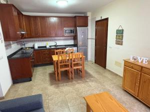 a kitchen with wooden cabinets and a table and chairs at Valthi in La Restinga