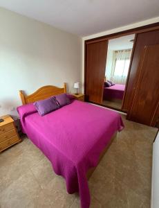 a bedroom with a large purple bed with a mirror at Valthi in La Restinga