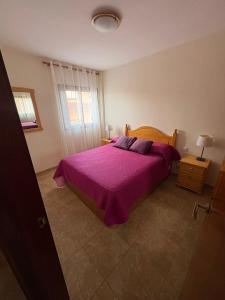 a bedroom with a bed with a purple bedspread at Valthi in La Restinga