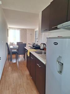 a kitchen with a white refrigerator and a table at Hermoso departamento cómodo in San Lorenzo Tetlixtac