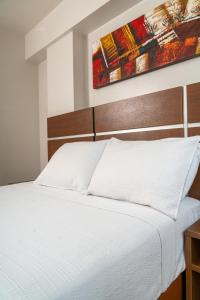 a bedroom with a white bed and a painting on the wall at Hotel Benidorm Panama in Panama City