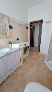 a bathroom with a sink and a washing machine at La tappa del vignaiolo B&B in Mamoiada