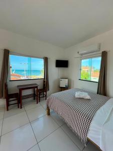 a bedroom with a bed and a desk and windows at Casa da Juma in Fortim