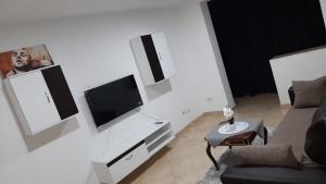 a living room with a couch and a tv on a wall at White Apartment in Bîrlad