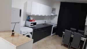 a kitchen with white cabinets and a black counter top at White Apartment in Bîrlad +9 photos