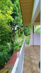 a porch with a white fence and trees at Shalom breaze in Gettapola +13 photos