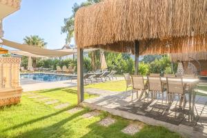 a patio with a table and chairs under a straw umbrella at Kalender Pansiyon Fethiye in Fethiye +15 photos