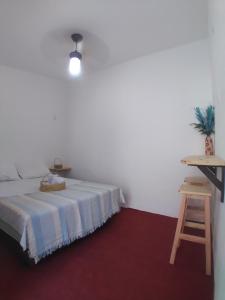 a white bedroom with a bed and a stool at Pousada Nosso Sonho in Natal