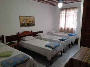 a group of three beds in a room at Psiu Lanches e Hotel Veraneio in Posse
