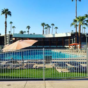 a fence with an umbrella next to a swimming pool at Ocotillo Lodge in Palm Springs