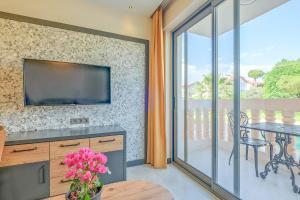 a living room with a tv and a table with flowers at Kalender Pansiyon Fethiye in Fethiye