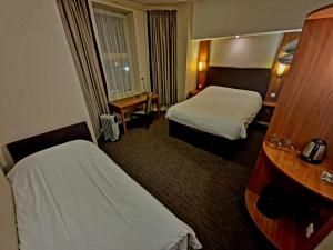 a hotel room with two beds and a desk at Charter Hotel Bournemouth in Bournemouth