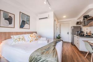 a bedroom with a white bed and a kitchen at Studio SP Congonhas, CEIC-Itaú, Expo-SP in São Paulo