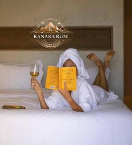 a woman laying in bed reading a book and holding a glass of wine at RUM KANARA BUBBLE lUXURY CAMP in Wadi Rum