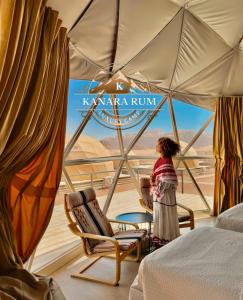 a woman standing in a room with a bed and a window at RUM KANARA BUBBLE lUXURY CAMP in Wadi Rum