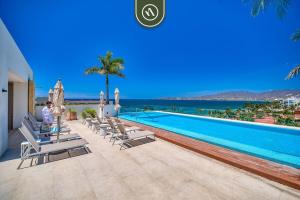 a swimming pool with chaise lounges and chairs next to the ocean at 2BR Condo with Rooftop Pool - 2 Min Walk to Beach in Bucerías